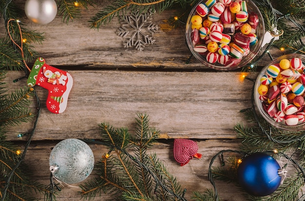 Caramelle, palline di Natale e rami di abete rosso su una superficie di legno