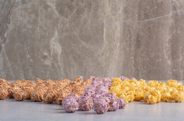 Caramelle popcorn ordinate per colore allineate sul marmo.