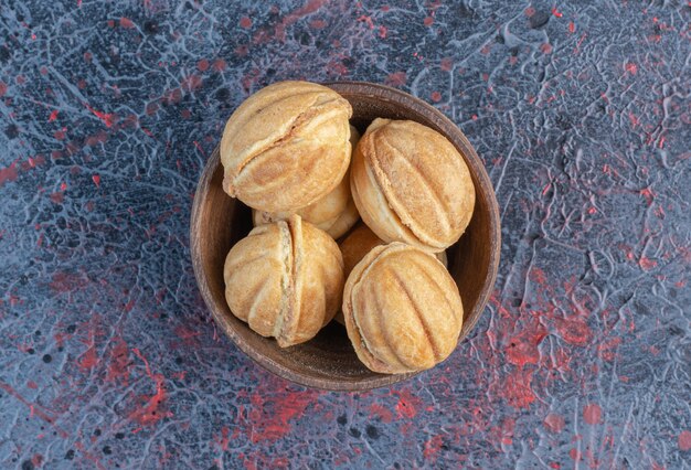 Caramello riempito palline di biscotti in una ciotola sul tavolo astratto.