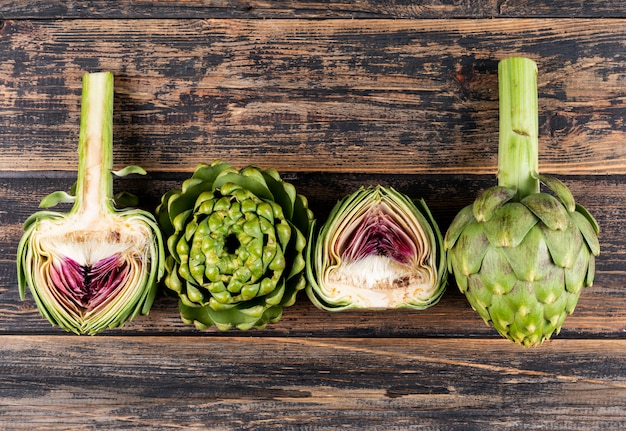 Carciofi interi e fette su un legno scuro. vista laterale.