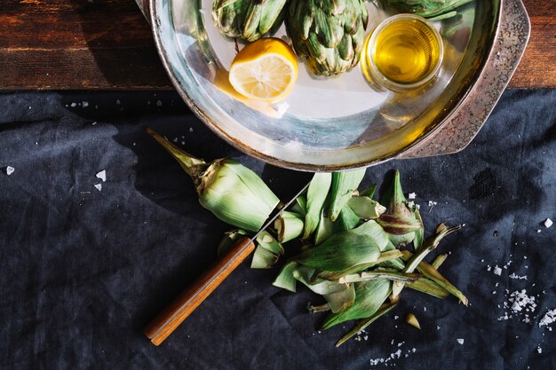Carciofo vicino al vassoio con limone e olio