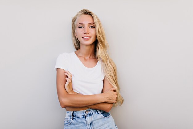 Carina donna abbronzata con gli occhi azzurri in posa in studio. Foto interna di una piacevole donna dai capelli lunghi