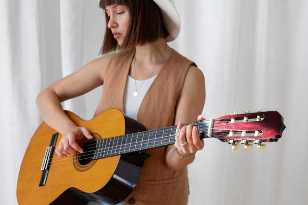 Carina giovane donna che suona la chitarra al chiuso