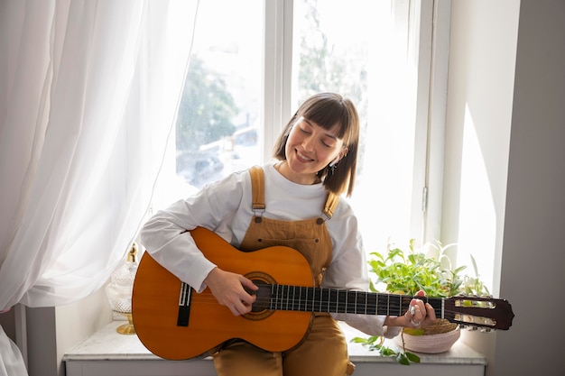 Carina giovane donna che suona la chitarra al chiuso