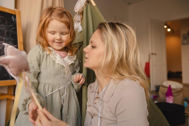 Carino bambina dalla pelle chiara con i capelli rossi gioca con la sua giovane madre a casa Concetto di trascorrere del tempo