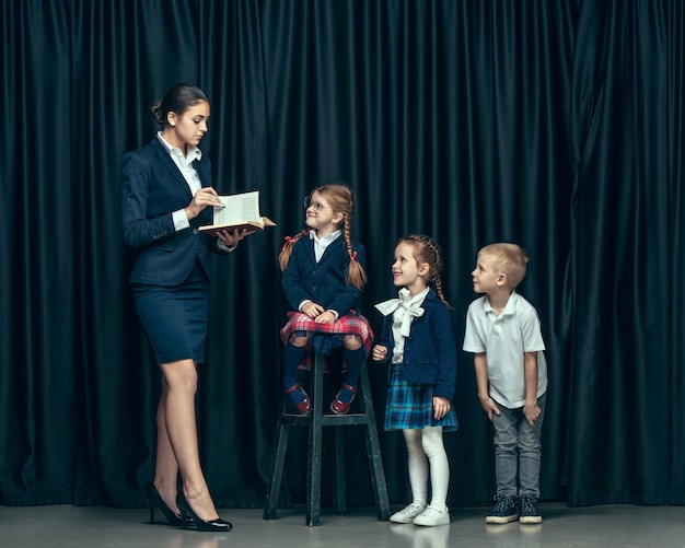 Carino bambini alla moda in studio scuro. Le belle ragazze adolescenti e il ragazzo in piedi insieme