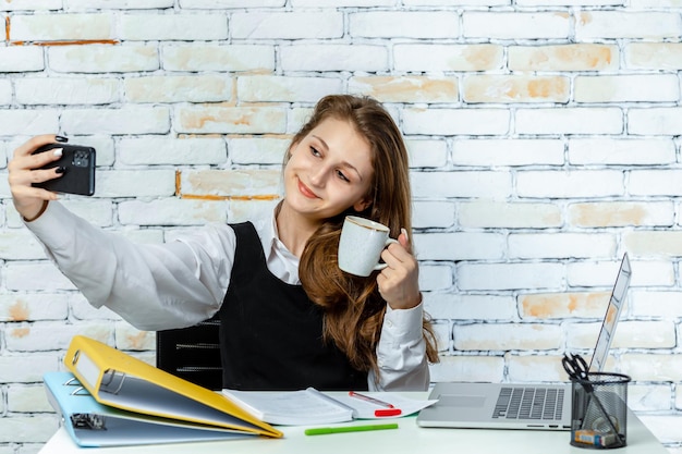 Carino giovane studente seduto su sfondo bianco e sul telefono Foto di alta qualità