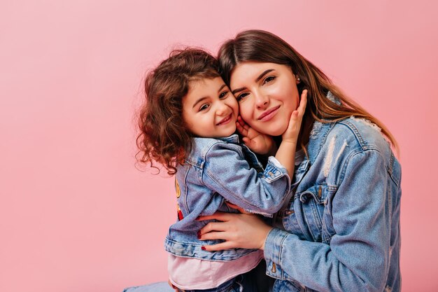 Carino ragazzino che abbraccia la madre Foto in studio di famiglia felice in abito denim