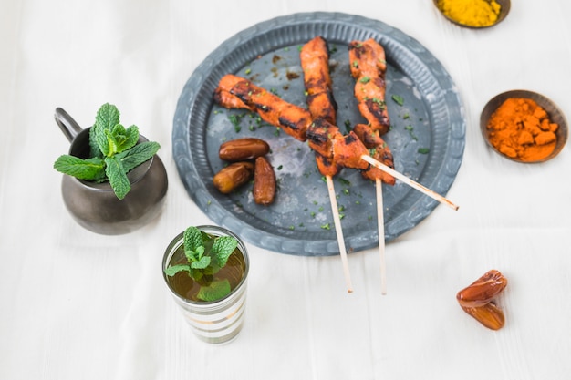 Carne alla griglia con prugne secche vicino a tazza, spezie e brocca