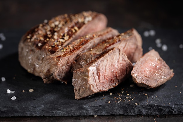 Carne alla griglia cotta fritta con spezie tagliate a fette servita su ardesia scura Primo piano