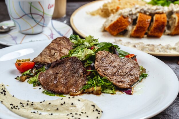 Carne arrostita con la vista dei lati di hummus del pomodoro dei funghi della lattuga