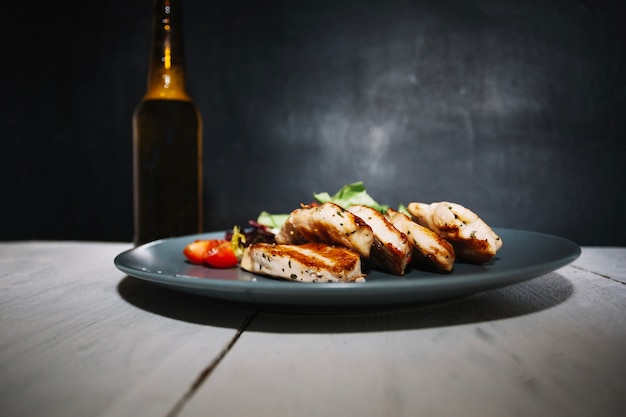 Carne arrosto e insalata vicino alla bottiglia