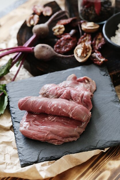 Carne cruda con ingredienti per cucinare il pasto