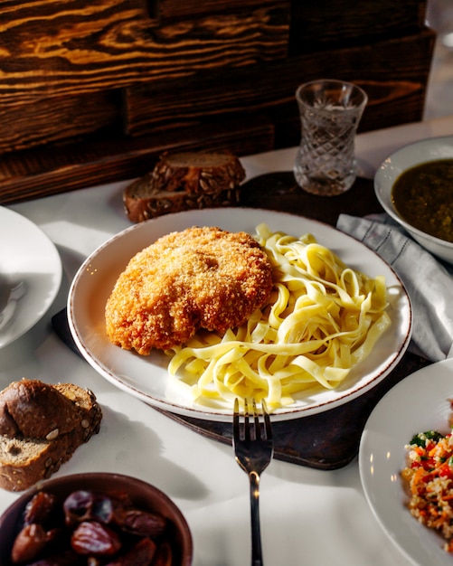 Carne della pasta di vista frontale dentro il piatto bianco con pane sul pavimento leggero