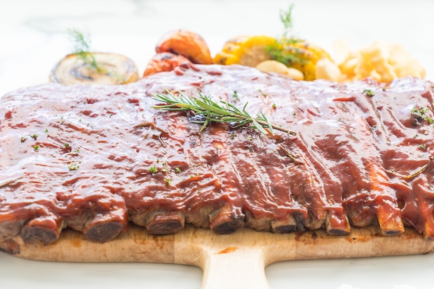 Carne di maiale alla griglia con salsa al barbecue e verdure e frech fries sul tagliere di legno