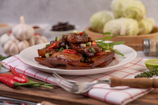 Carne di maiale dolce su un piatto bianco con scalogno tritato, peperoncino, lime, cetriolo, pomodoro e aglio.