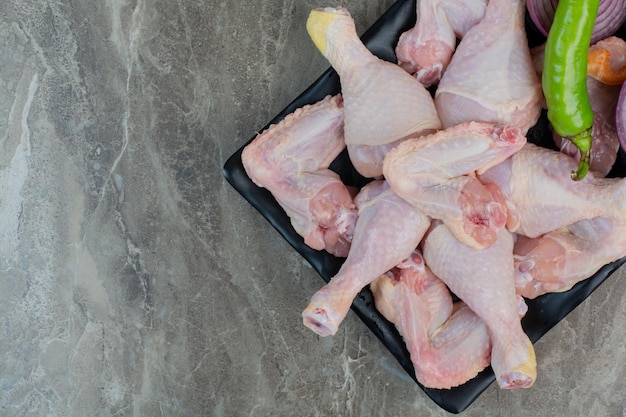 Carne di pollo cruda con peperoni e cipolla su piatto scuro. Foto di alta qualità