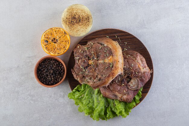 Carne fresca affettata con verdure fresche poste su un tavolo di pietra.