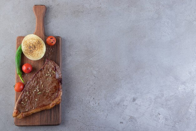 Carne fresca affettata con verdure fresche poste su uno sfondo di pietra.