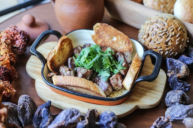 Carne in padella sulla tavola di legno con verdure e panino con semi di sesamo