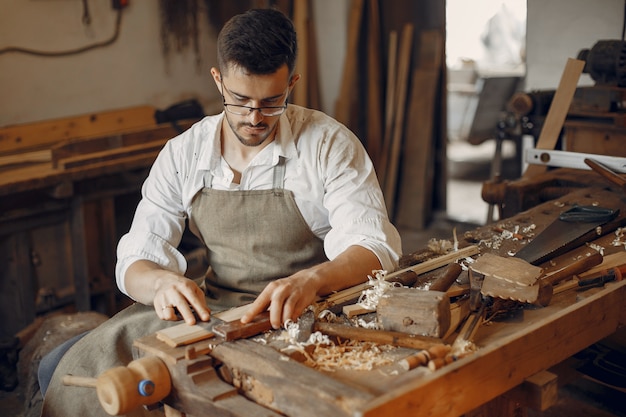 Carpentiere bello che lavora con un legno