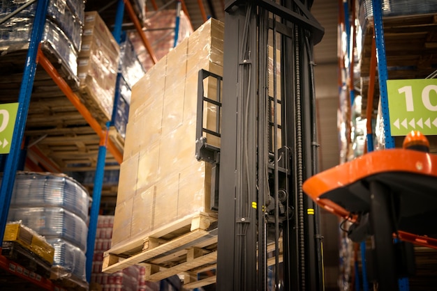 Carrello elevatore industriale macchina sollevamento tavolozza piena di scatole di cartone e posizionarli sugli scaffali nella struttura di magazzino di distribuzione