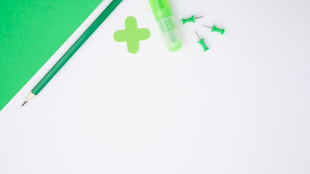 Carta artigianale verde; matita; incollare e spingere il perno sulla superficie bianca