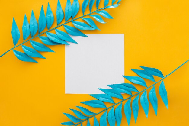 Carta bianca con foglie blu su sfondo giallo