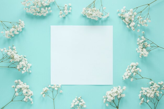 Carta bianca con rami di fiori sul tavolo