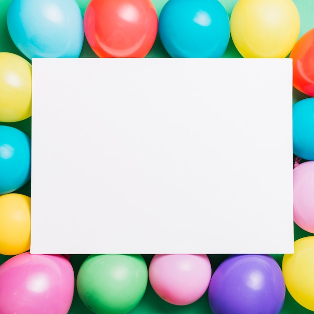 Carta bianca della plancia sopra i palloncini colorati