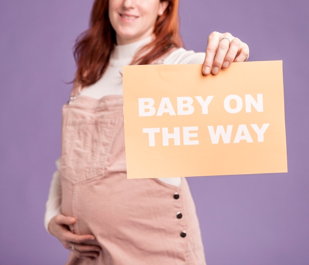 Carta della tenuta della donna incinta del primo piano con il bambino sul messaggio di modo