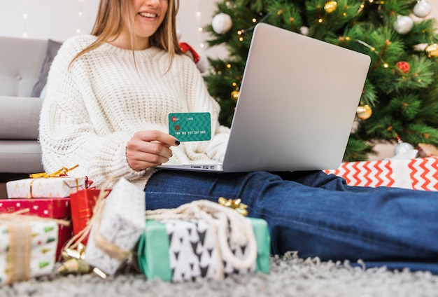 Carta di credito e computer portatile sorridenti della tenuta della donna