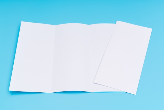 Carta di modello bianco trifold su sfondo blu.