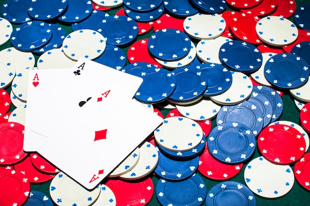 Carta di tre assi sul bianco; fiches del casinò blu e rosso