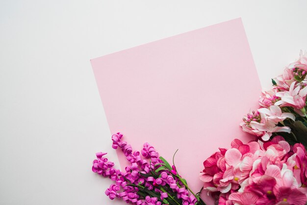 Carta rosa vuota con fiori colorati su sfondo bianco