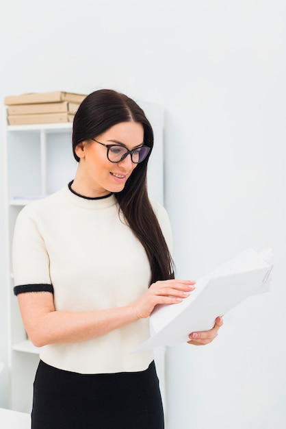 Carte della lettura della giovane donna in ufficio