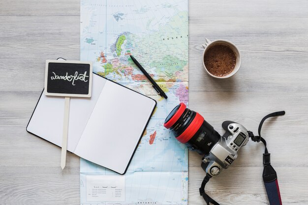 Cartello Wanderlust sul notebook con mappa, caffè e fotocamera sulla scrivania