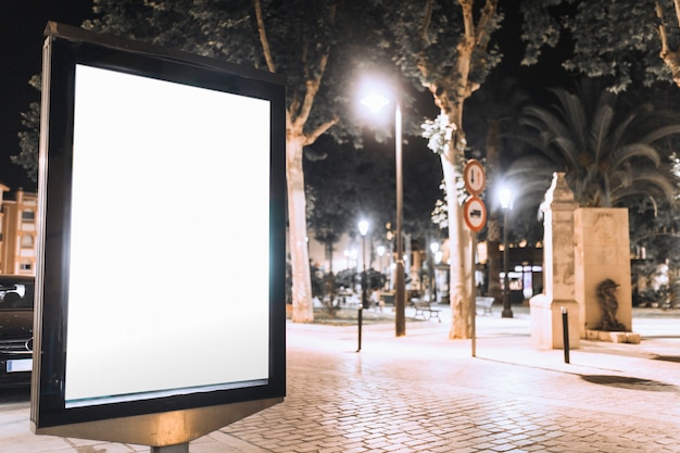 Cartellone bianco verticale sulla strada di notte