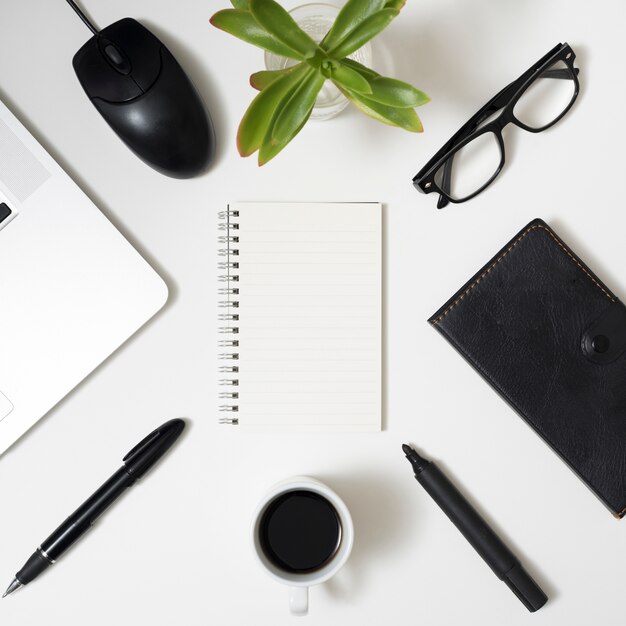 Cartoleria per ufficio; il computer portatile; occhiali e tazza di caffè sopra sfondo bianco