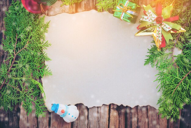 Cartolina di Natale in bianco sul fondo di legno di struttura con altri che decorano gli oggetti