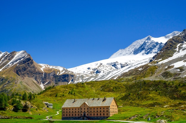 Casa circondata da montagne rocciose coperte di verde e neve nel Vallese in Svizzera