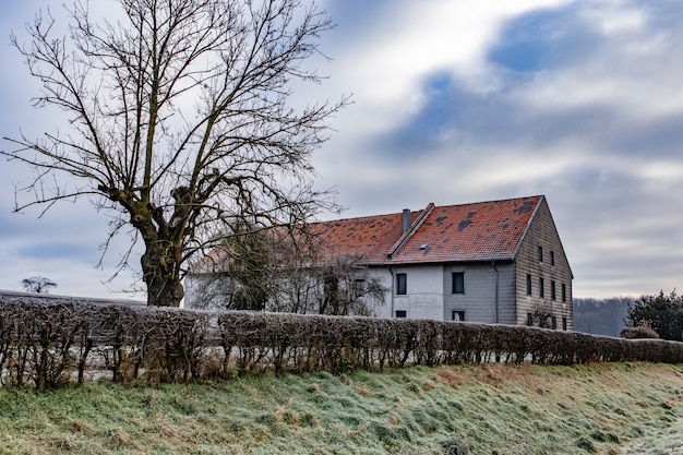 Casa immersa nel verde con colline sotto un cielo nuvoloso sullo sfondo