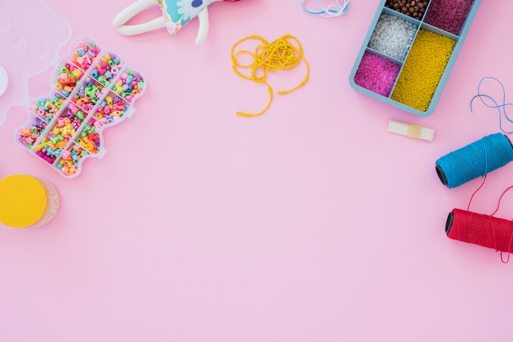 Foto gratuito cassa variopinta delle perline e bobine del filato su fondo rosa