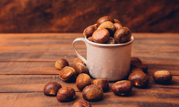 Castagne in una tazza e intorno su un tavolo di legno scuro