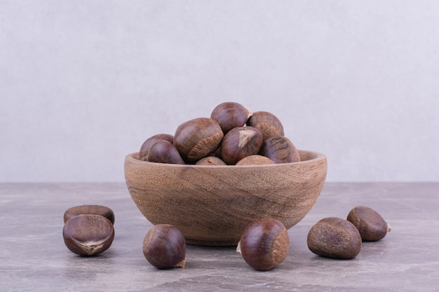 Castagne marroni in una tazza di legno sulla pietra