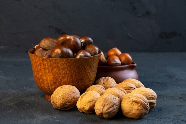 Castagne vista laterale in una tazza con nocciole e noci