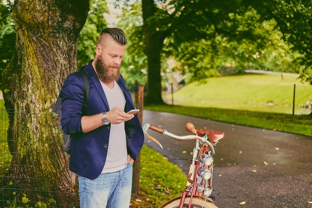 Casual maschio barbuto in un parco colloqui tramite smartphone.