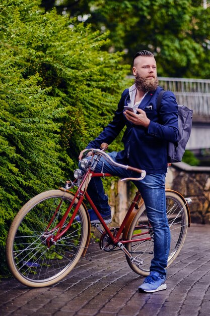 Casual maschio barbuto in un parco colloqui tramite smartphone.