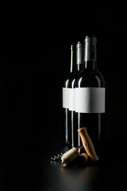 Cavatappi e tappi di sughero vicino alle bottiglie di vino