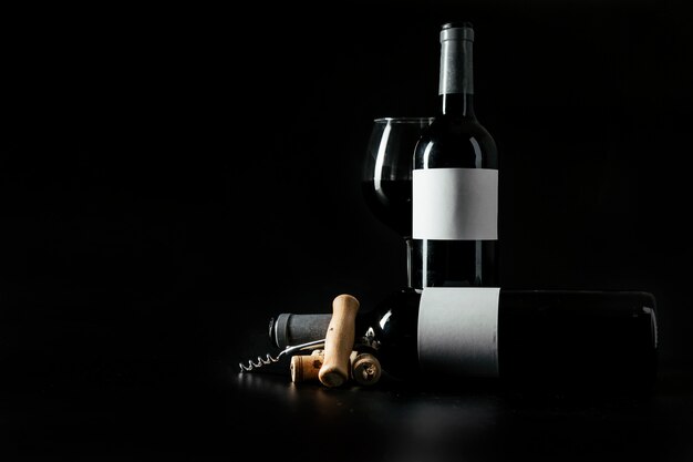 Cavatappi e tappi di sughero vicino bottiglie e bicchiere di vino